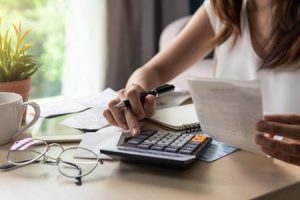 Hand holding a pen typing on calculator