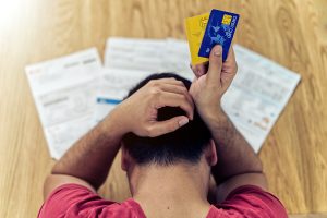 an ariel view of a stressed out man holding credit cards next to a table of bills