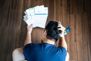 an aerial view of a stressed out man looking at piles of bills and credit cards considering debt payoff strategies