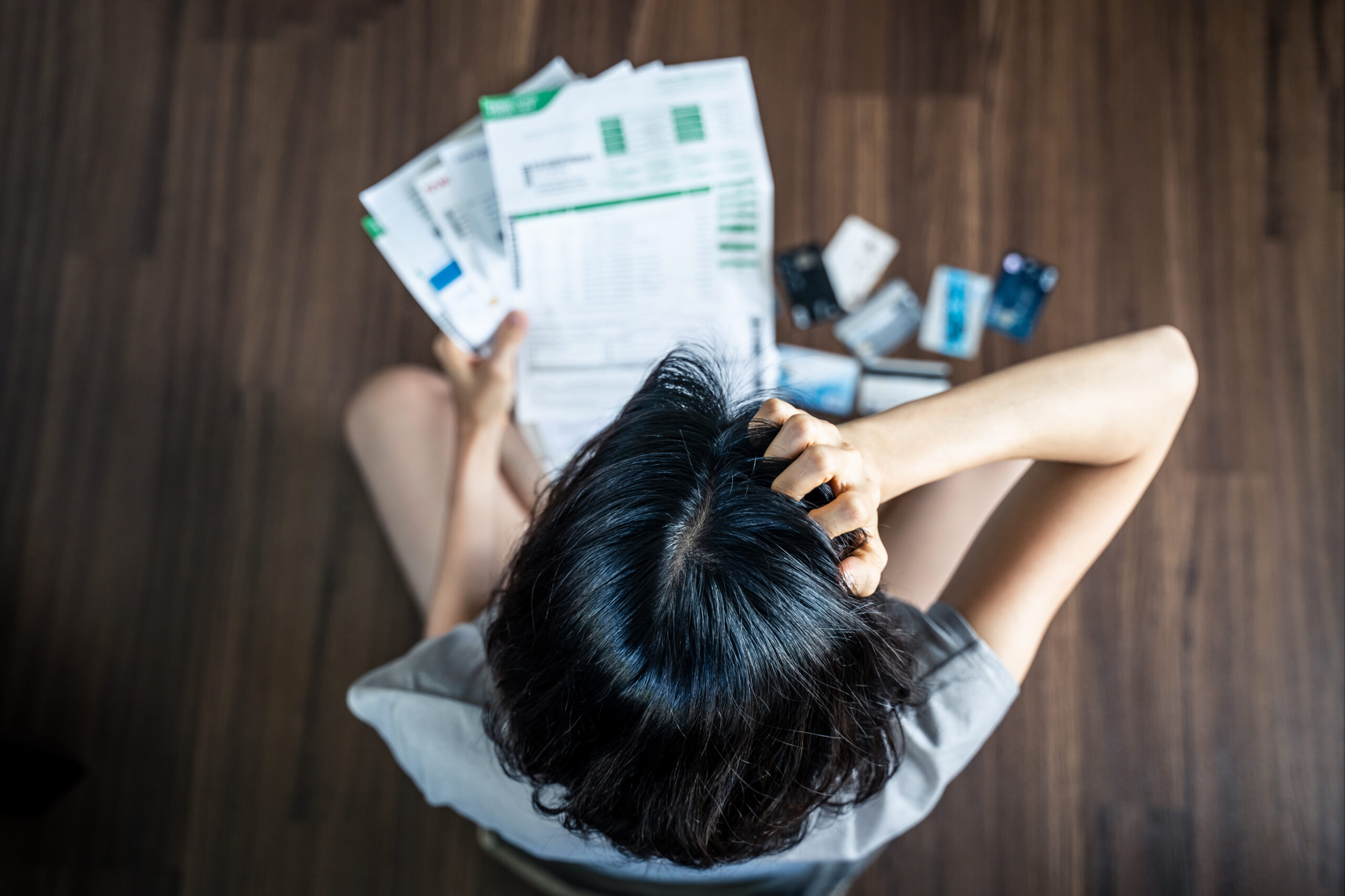 a woman reviews her many credit card and loan statements to see how debt consolidation could improve her credit score