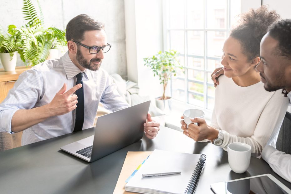 A credit union representative discusses debt-to-income ratio with a happy couple.