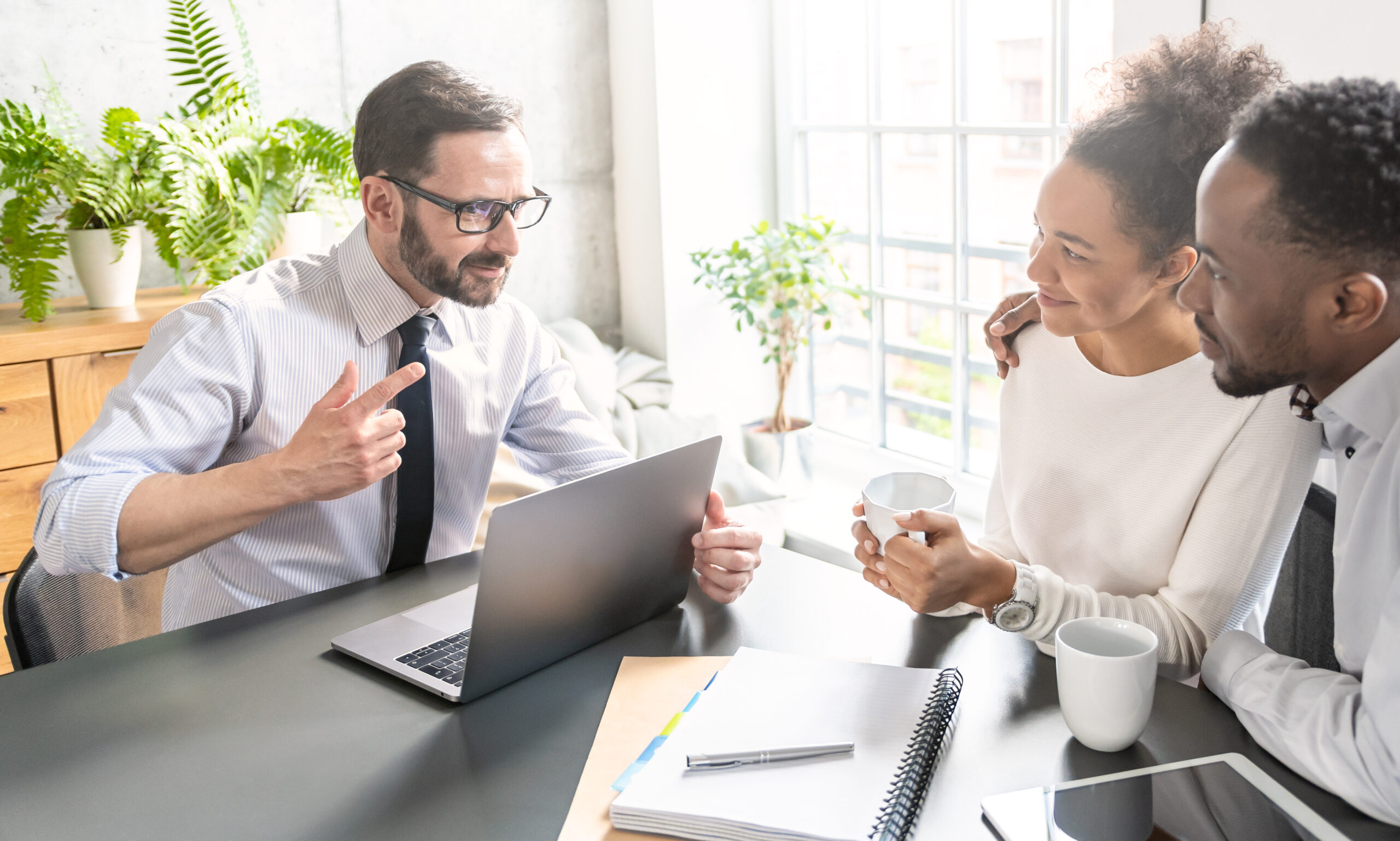 A credit union representative discusses debt-to-income ratio with a happy couple.