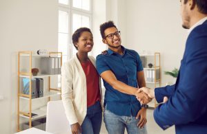 A happy couple shakes hands with a credit union representative after discussing refinancing a HELOC or home equity line.