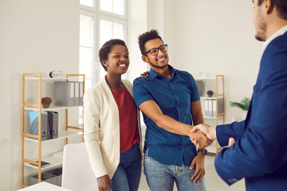 A happy couple shakes hands with a credit union representative after discussing refinancing a HELOC or home equity line.