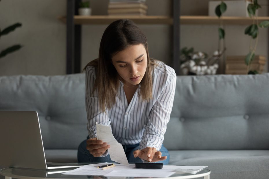 A young woman reviews her bills to see if she should apply for a personal loan to build credit.